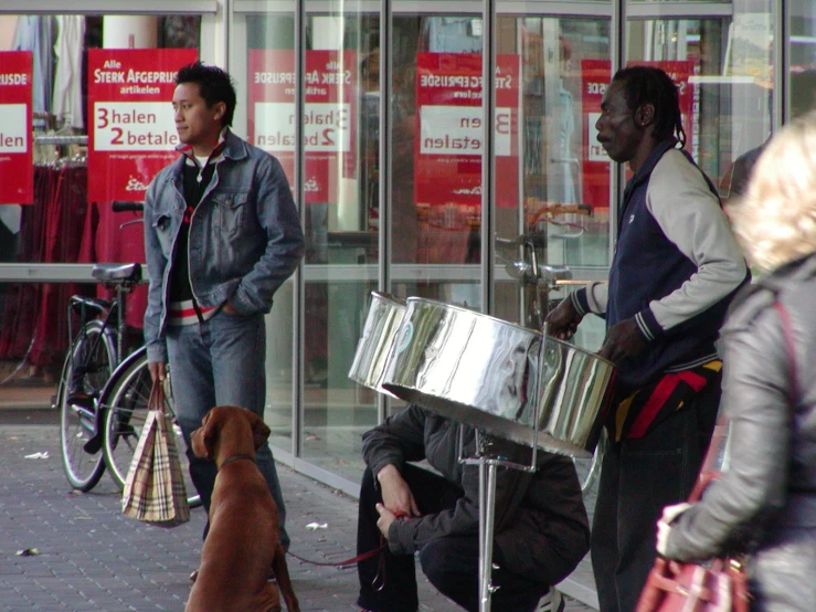 two men and a dog with musical instruments in front of shops