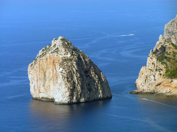 there are two large rocks on a hill in the ocean