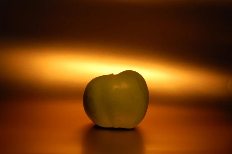 an apple sits alone in a dark room