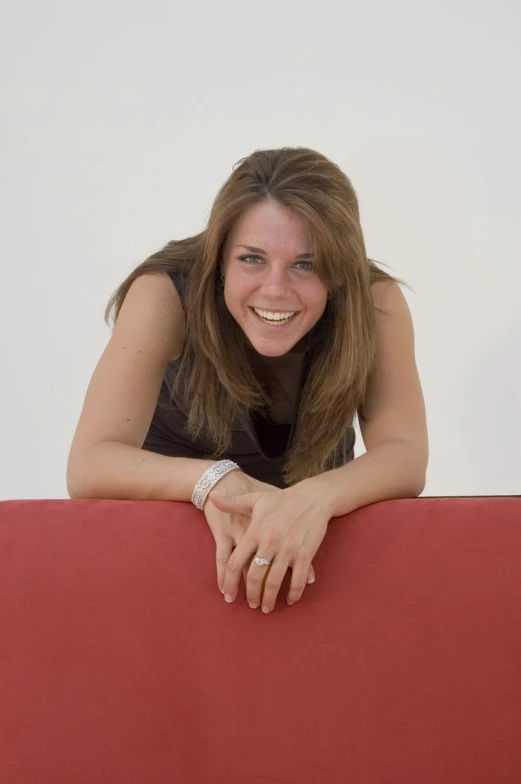 a woman posing for a picture leaning over a red couch