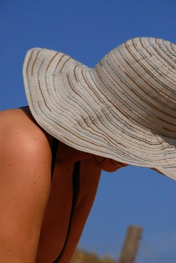 a woman in a tan and white hat leaning over