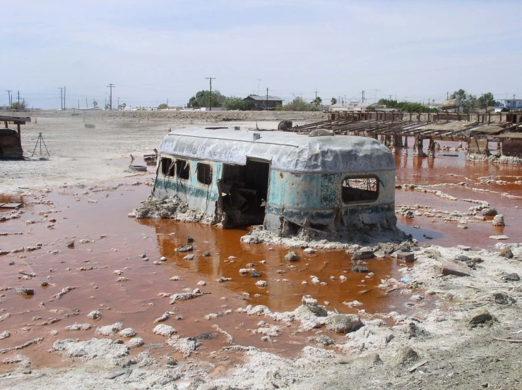 a burnt bus sitting on top of a muddy road
