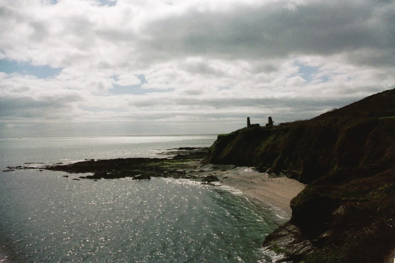 two people standing on top of a grassy hill near the ocean