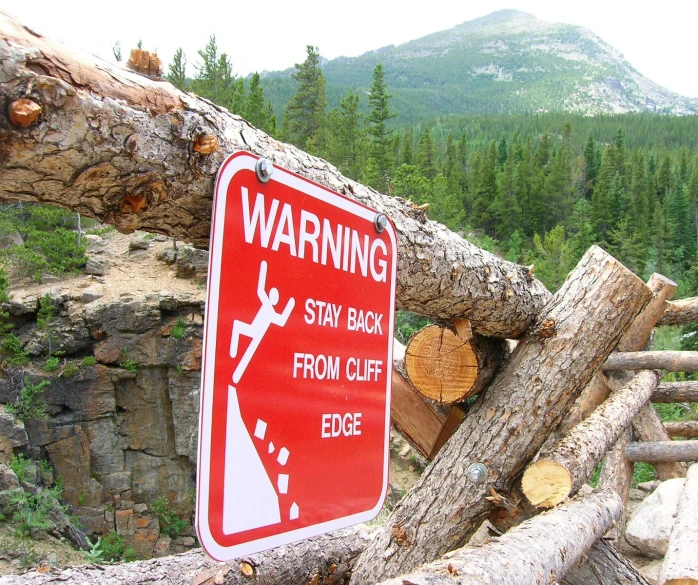 a red warning sign sitting on the side of a tree