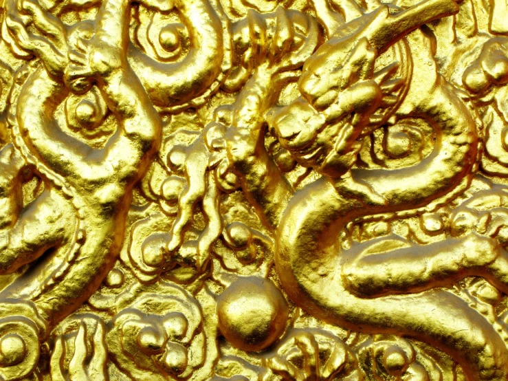 an intricate gold wall with multiple faces and vines