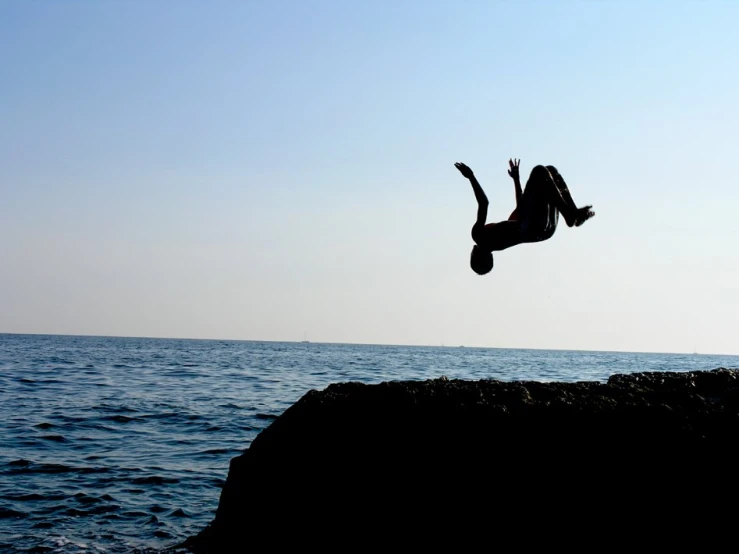 a man falling off a cliff above the ocean