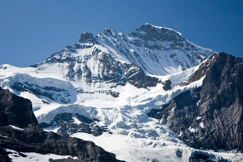 a very tall mountain covered in snow on a sunny day