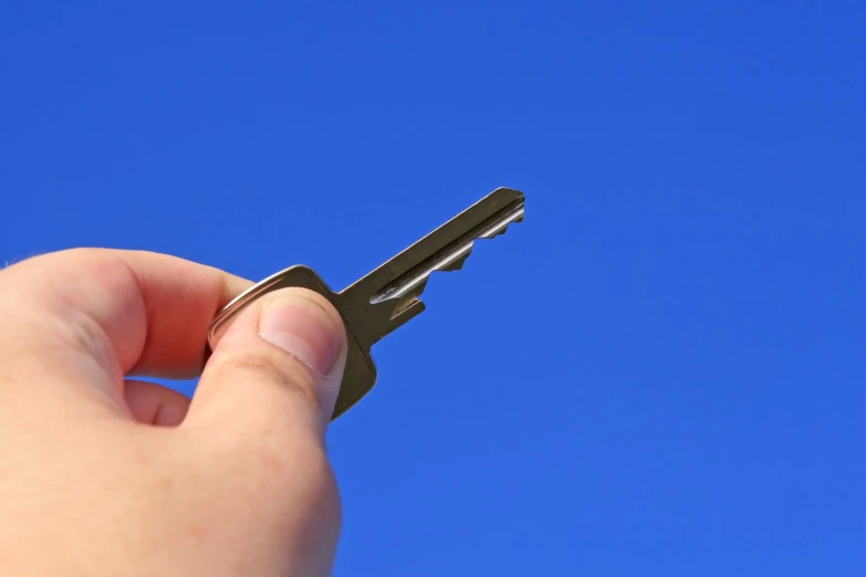 there is a key in the hand with blue sky in background