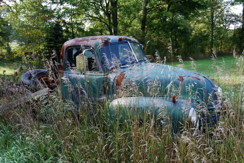 an old truck is sitting in the grass