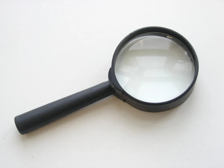 a magnifying glass on a white table with an empty liquid tube