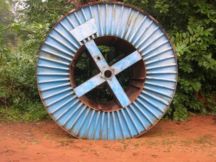 a big metal wheel with some trees around it