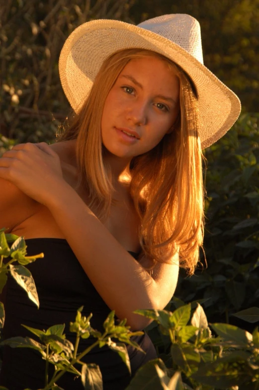 a girl in a hat standing amongst some leaves