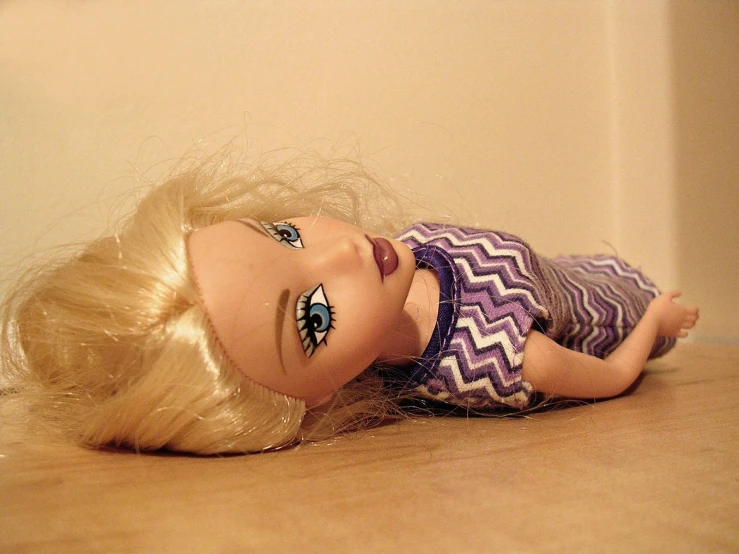 a doll laying on the floor with very long blonde hair