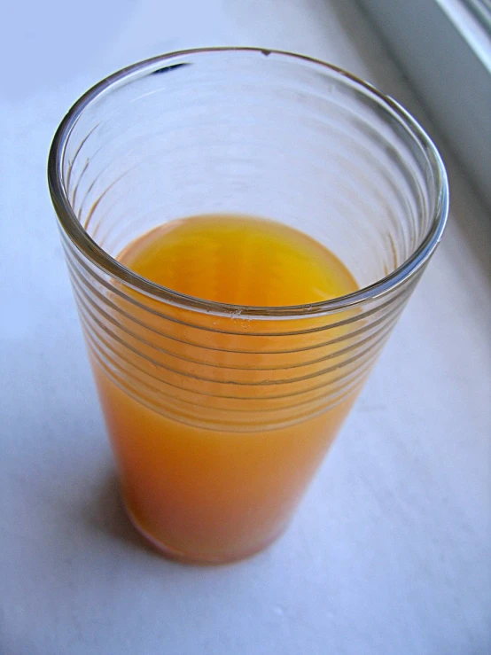 a glass cup filled with liquid near a window