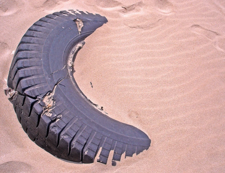 an open tire laying in the sand on a beach