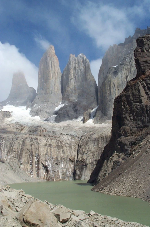 there is a group of mountains with a green lake