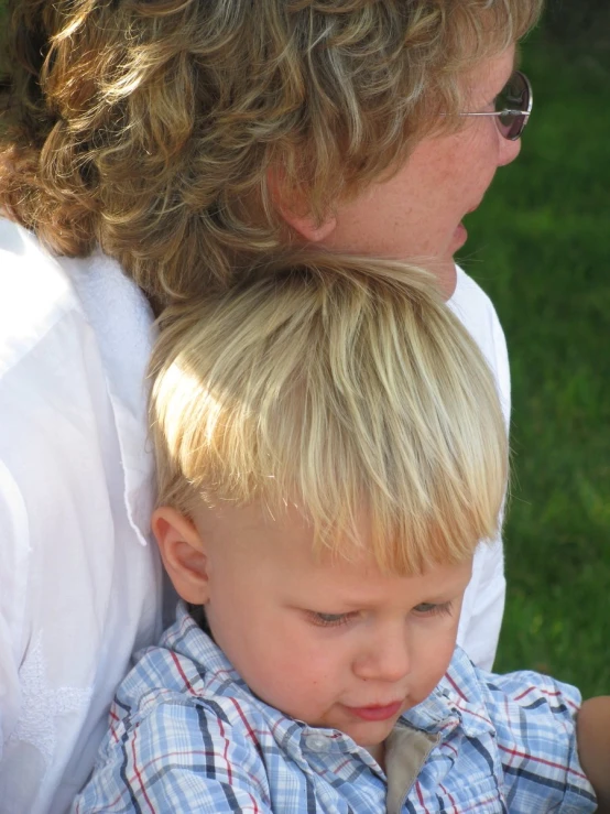 a woman sitting in front of a small boy who is holding a white frisbee