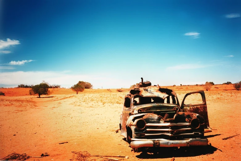 two abandoned military trucks sitting on a dry field