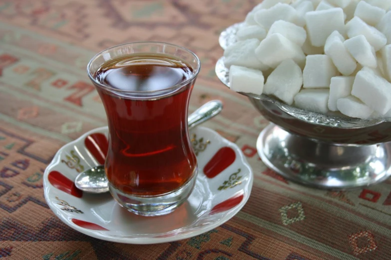 a saucer with sugar cubes on a plate and cup of tea on a plate