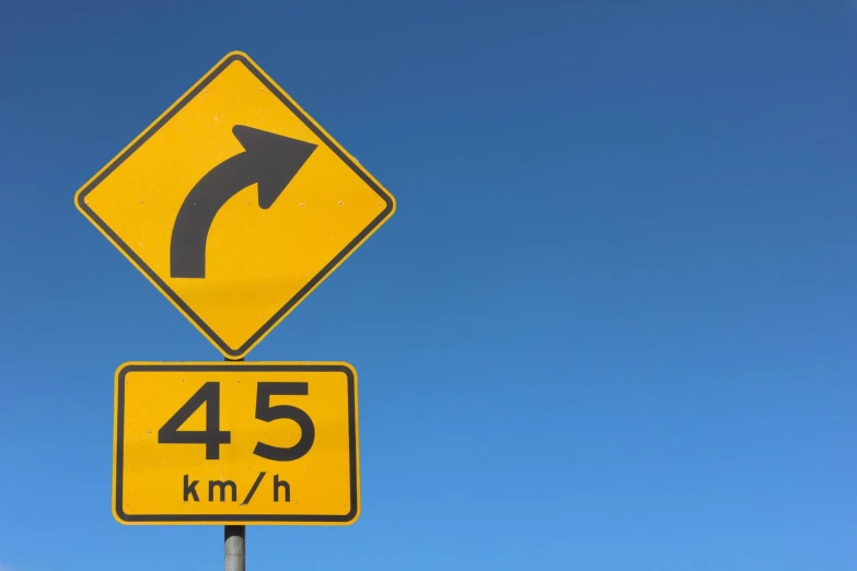 a yellow street sign reading the width of arrows in the sky