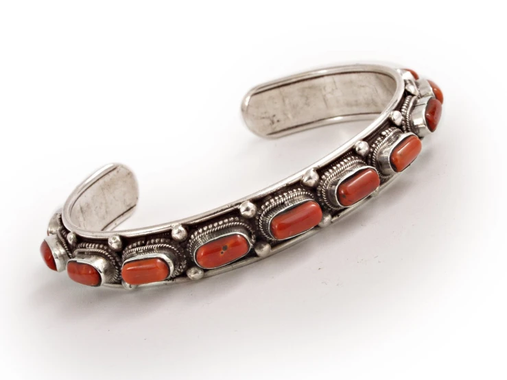 an orange stone is shown in a silver celet