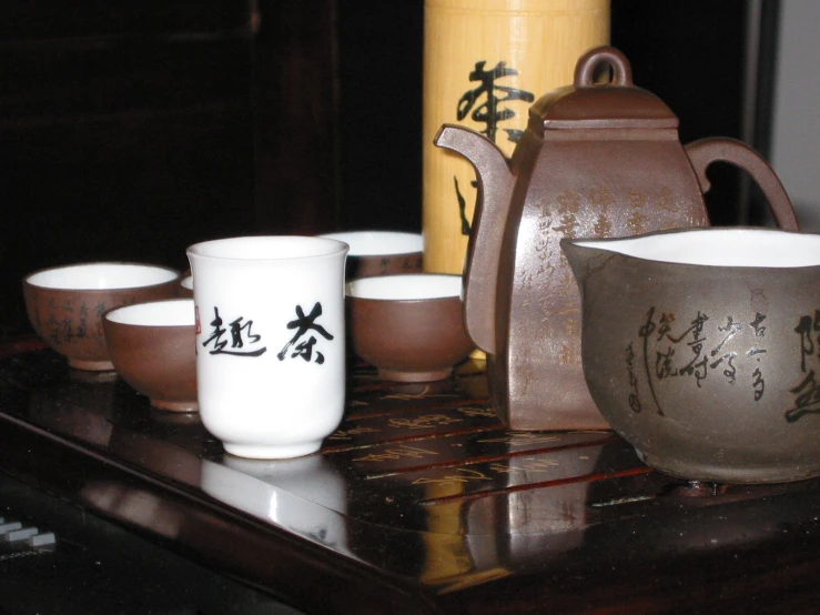 a table topped with tea cups and chinese writing on saucers