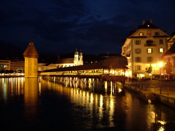 a night view of buildings in the water and lights from around