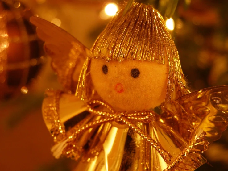 a golden angel doll ornament with lights in the background