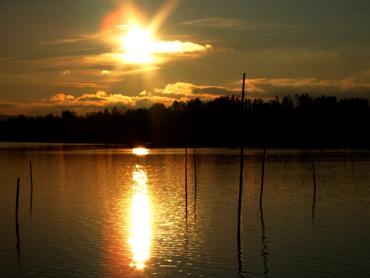 sun shines brightly as the reflection of a boat in the water