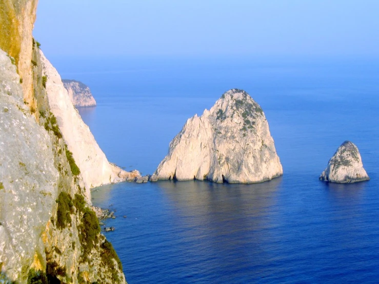 three rocks are on the sea with large rocks sticking out of them