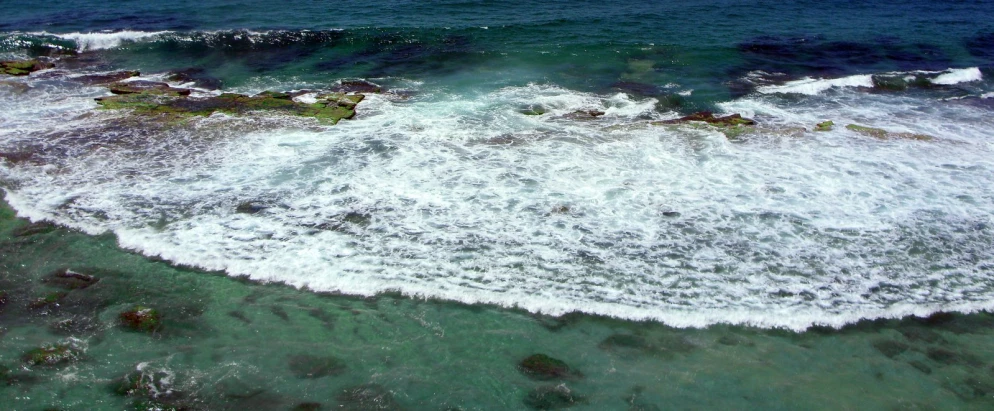 an aerial view of the ocean waves and rocks