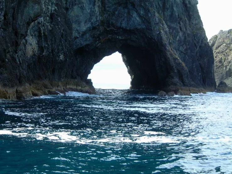 there is an ocean and cliff with a big tunnel