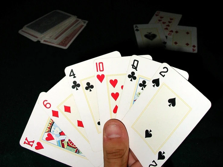 a hand is holding four cards on top of the table