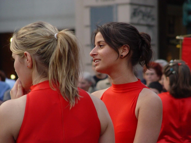 there are two woman talking and standing near one another