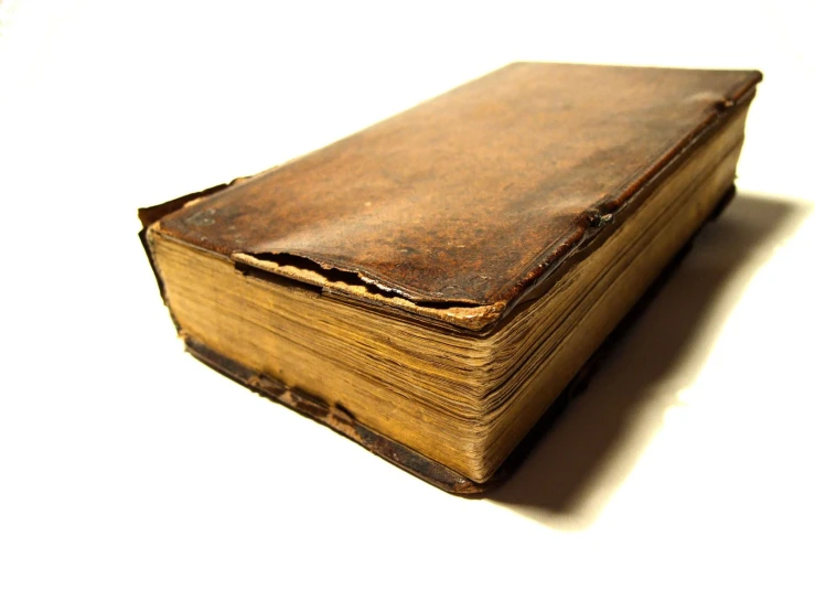 a small antique book is lying open on a white surface