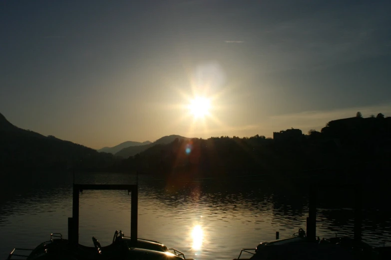 the sun rises over mountains behind a lake