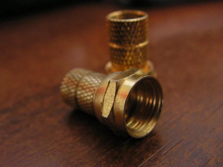 a gold plated coupler sitting on top of a wooden table