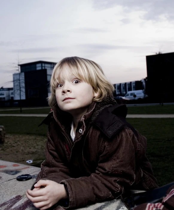 the little boy is sitting in front of his suitcase