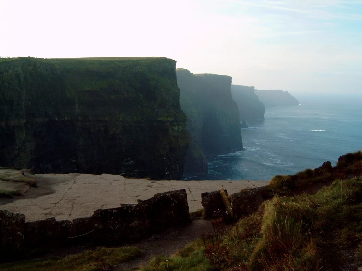 a bench at the edge of a cliff by the ocean