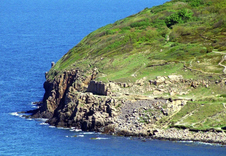 a long cliff is on the side of a big body of water