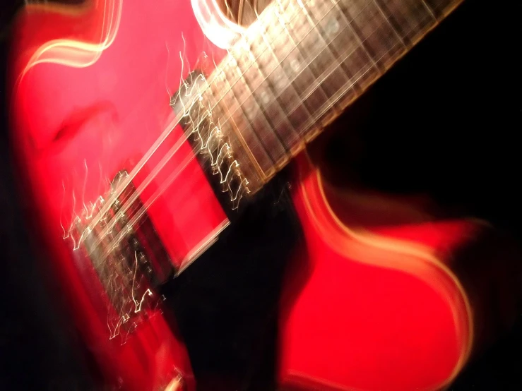 blurry pograph of an acoustic guitar with red tone and black background