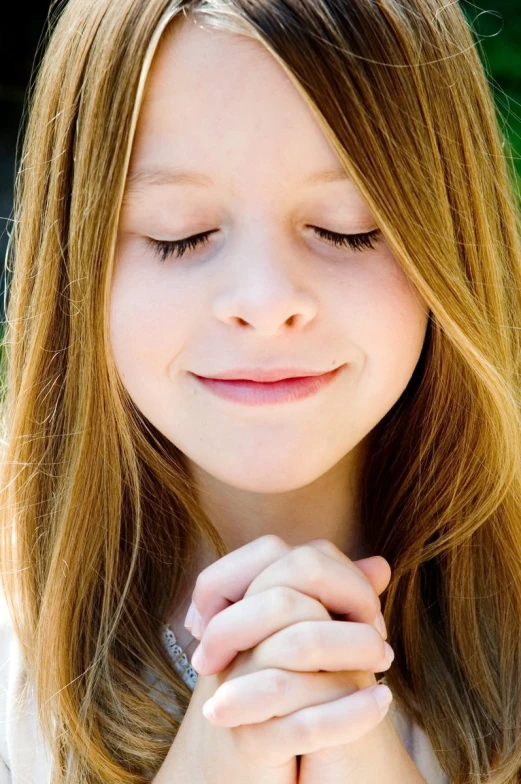 a little girl with her hands clasped in a praying pose