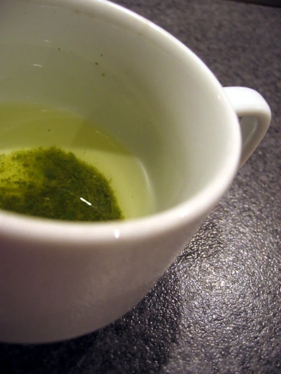 a white cup filled with green liquid on top of a table