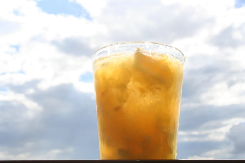 a tall glass with yellow liquid sitting on a ledge