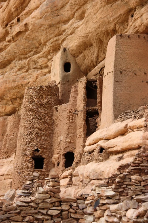 the cliff is made of red clay and has a small structure next to it