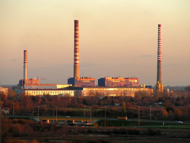 three stacks of smoke rise from a factory