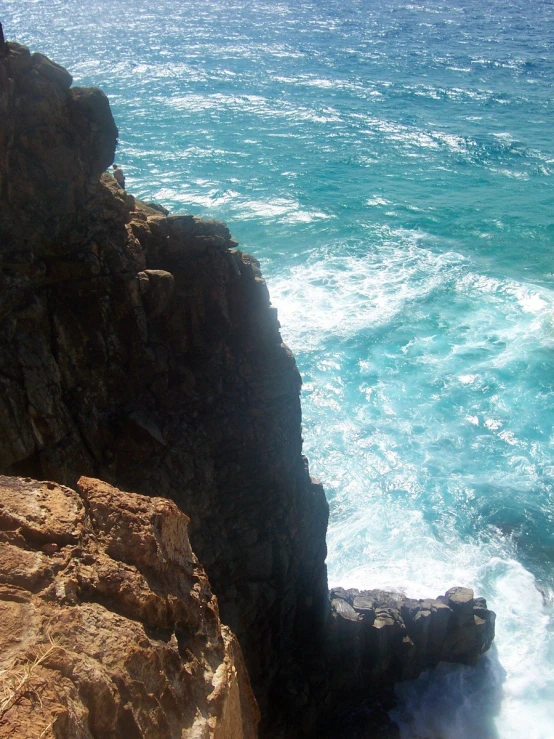 a person climbing over the edge of a cliff near the ocean