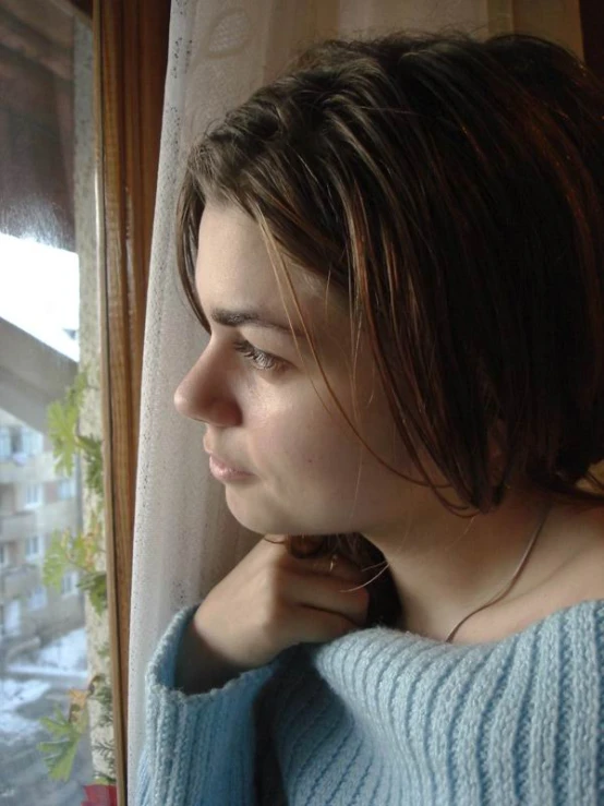 a girl looking out a window by some sheer fabric