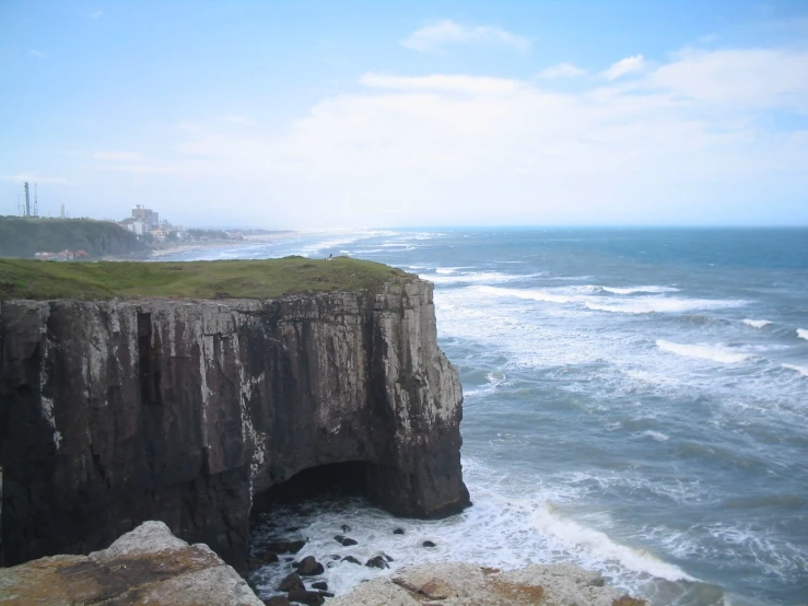 a cliff face with an ocean on the side near the water