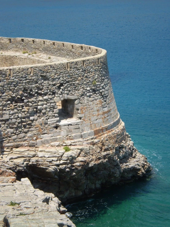 a very old stone tower above the ocean